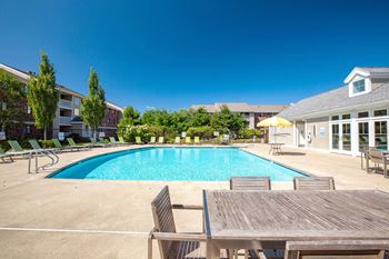 A swimming pool with a wooden table and chairs around it